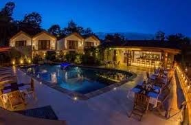 Luxurious twilight view of an illuminated residential compound with pool, spa, and multiple buildings surrounded by landscaping