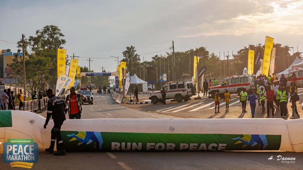 Peace Marathon starting line with crowds of runners and spectators gathered under yellow banners on a sunny street