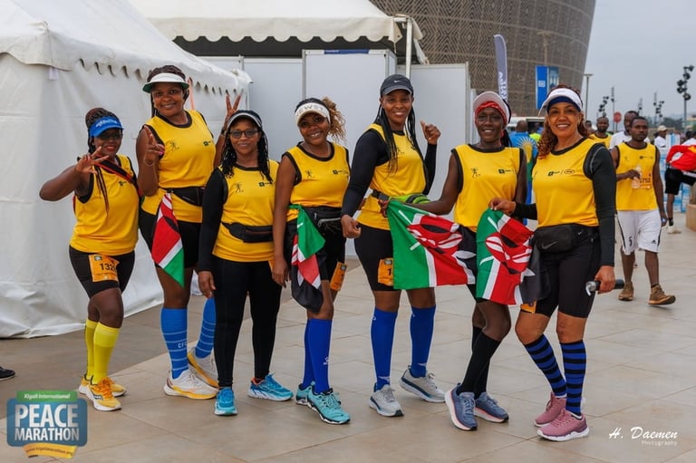 Group of eight runners in yellow and black athletic gear posing together at a marathon event with white tent and city buildings in background
