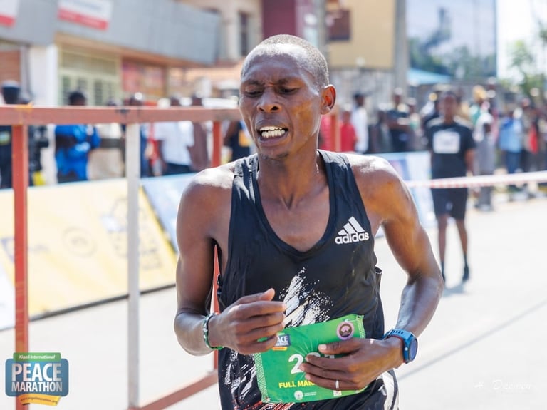 Marathon runner in black Adidas shirt competing in Peace Marathon race with crowd and barriers visible in background