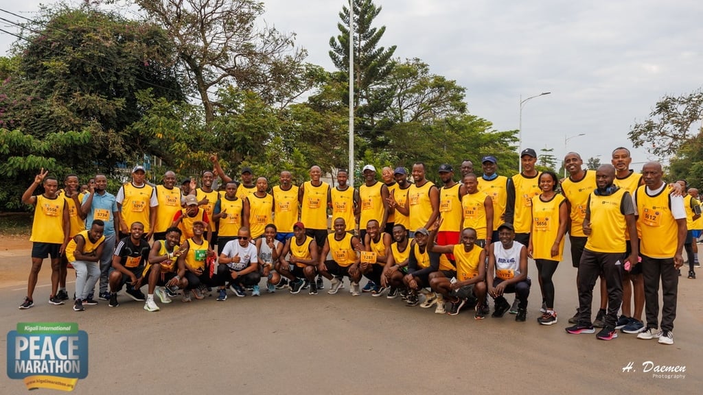 Large group of people wearing yellow vests posing for a photo at a Peace Marathon outdoor event