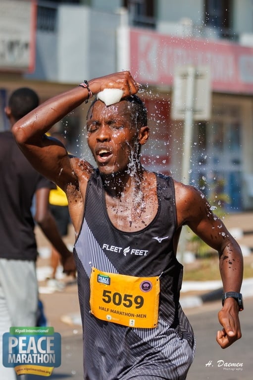 Male runner wearing bib number 5059 splashing water on his face during a half marathon race on a sunny day