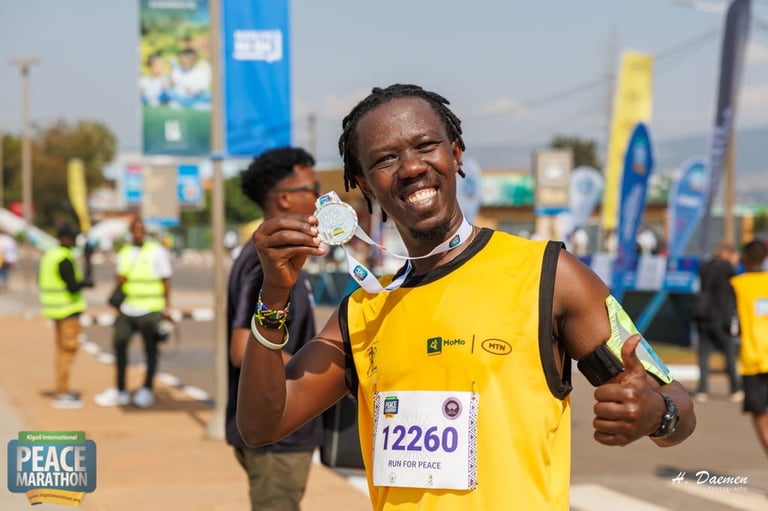 Smiling male marathon runner in yellow vest displaying medal at finish line with spectators in background