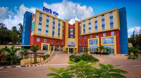 Colorful Park Inn hotel building with yellow, red, and blue exterior walls under a bright blue sky with white clouds